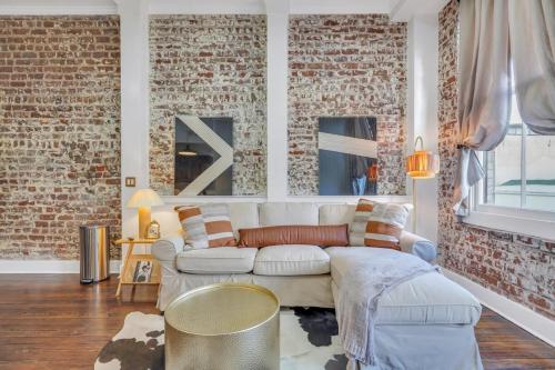 a living room with a white couch and a brick wall at Broughton Bliss Loft- City Market Plant Riverside in Savannah
