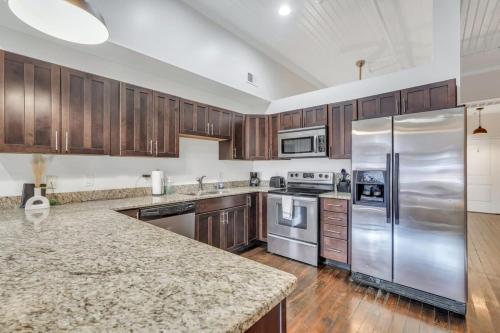 a kitchen with wooden cabinets and stainless steel appliances at Broughton Bliss Loft- City Market Plant Riverside in Savannah