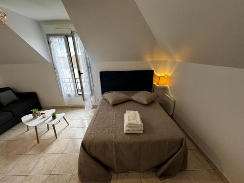 a bedroom with a large bed and a couch at Le studio du 72 in Bussy-Saint-Georges