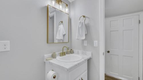 a white bathroom with a sink and a mirror at Eagle's Roost Retreat - Near GSU in Statesboro