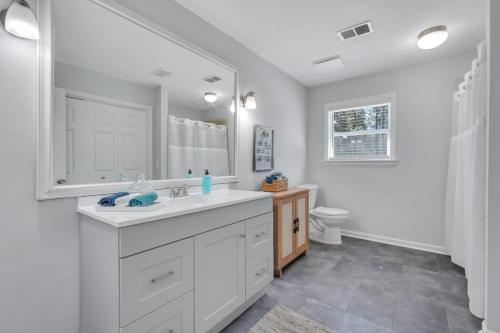 een witte badkamer met een wastafel en een toilet bij Southern Splash Retreat Poolside Paradise by GSU in Statesboro
