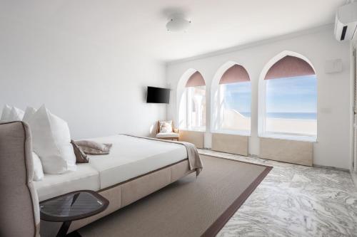um quarto branco com uma cama e 2 janelas em Buccara Villa Scirocco em Villajoyosa