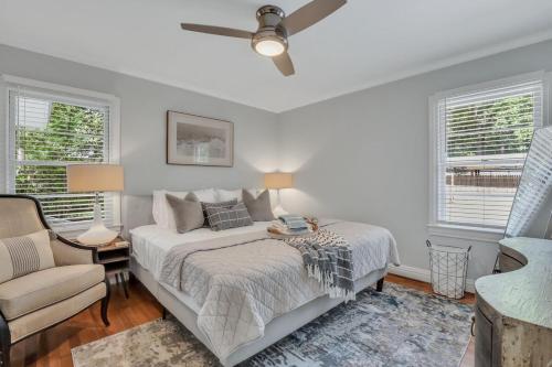 a bedroom with a bed and a chair and windows at Mid-Century Bungalow - Blue Mile & Close to GSU in Statesboro