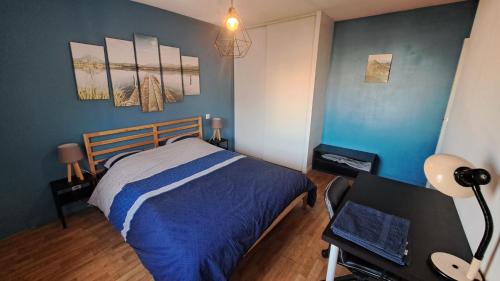 a bedroom with a bed with blue walls and a desk at Appartement cosy 3 pièces avec garage privatif in Saint-Priest