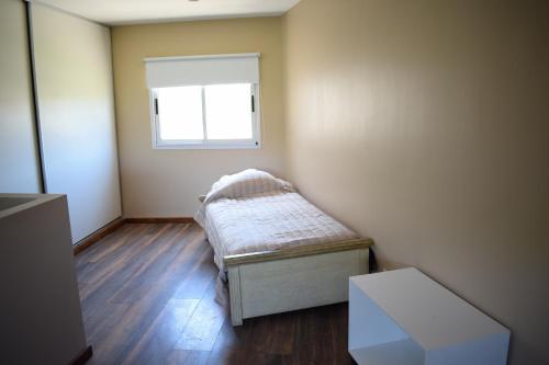 um pequeno quarto com uma cama e uma janela em Duplex Jacaranda I em Ciudad Evita