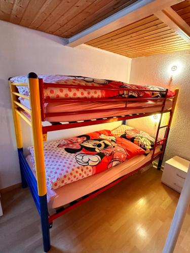 two bunk beds with a mickey mouse comforter at Bijouswiss " Yellow House" in Oberterzen