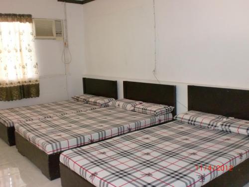 two beds are sitting in a room with a window at Pabua's Cottages in Mambajao