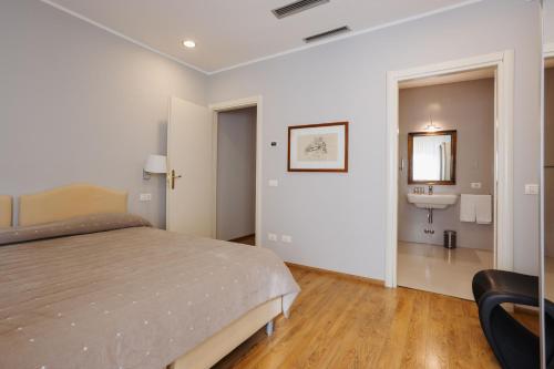 a bedroom with a bed and a bathroom with a sink at Palazzo Dalla Rosa Prati in Parma