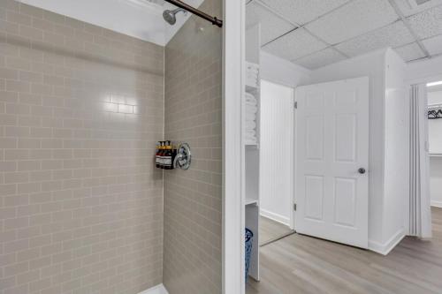 een badkamer met witte tegelmuren en een witte deur bij Eagle's Nest - Upscale Loft Downtown Close to GSU in Statesboro