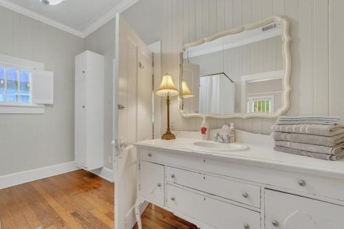 W białej łazience znajduje się umywalka i lustro. w obiekcie Historic Southern Home - close to downtown and GSU w mieście Statesboro