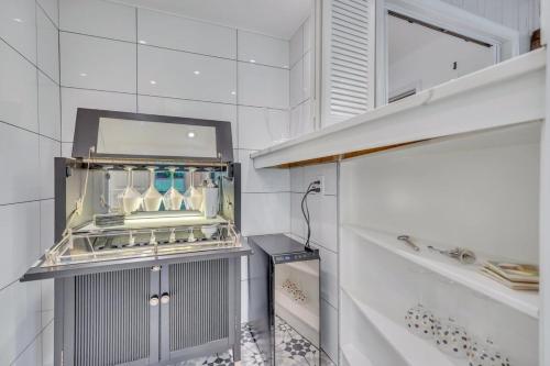 a kitchen with white tiled walls and a shelf at The Grey - Large Eclectic and Quiet Home in Statesboro