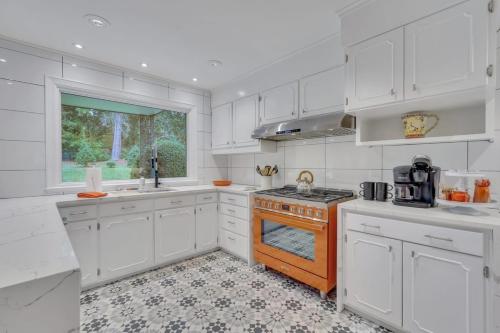 a kitchen with white cabinets and an orange stove top oven at The Grey - Large Eclectic and Quiet Home in Statesboro