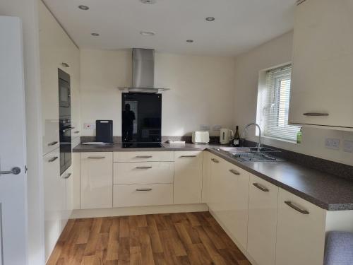 a kitchen with white cabinets and a wooden floor at Estuary view in Fleetwood