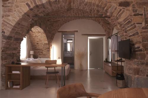 a bedroom with a bed and a table in a stone wall at enδόtera chios apartments in Chios