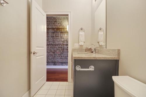a bathroom with a sink and a brick wall at Downtown Loft- Steps away from Plant Riverside! in Savannah