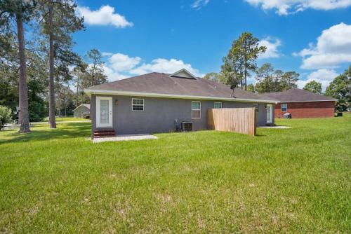 a house in a field with a grass yard at Charming Gray Home- 5 mins from GSU! in Statesboro