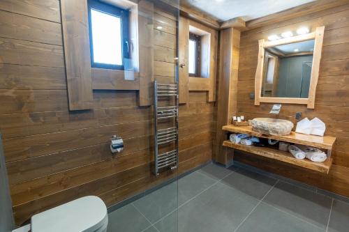 uma casa de banho com paredes de madeira, um lavatório e um espelho. em V Chalet Residence em Velingrad