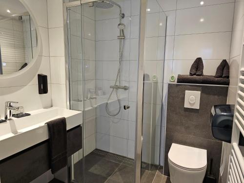 een badkamer met een douche, een toilet en een wastafel bij Hotel Restaurant Solskin in Vlissingen