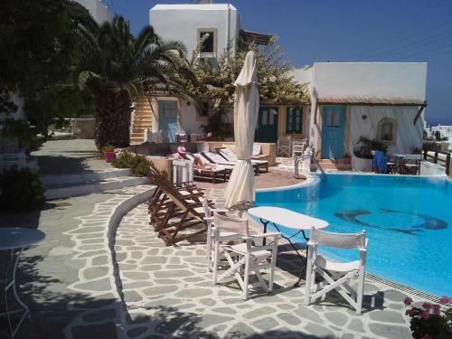 a pool with chairs and umbrellas next to a house at Ampelos in Chora Folegandros