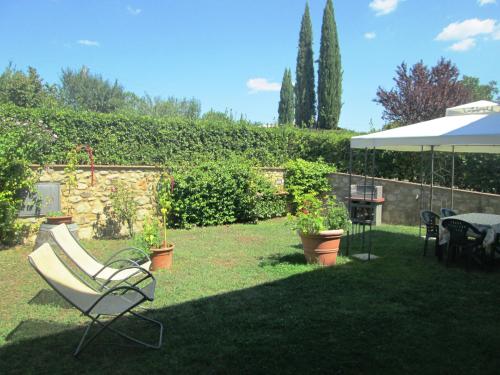 einen Garten mit einem Stuhl, einem Tisch und einem Sonnenschirm in der Unterkunft Casa ai Carfini in Poggibonsi