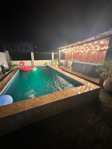 Cloud9 Luxury Apartments في آكرا: مسبح في الليل مع عوامة حمراء فيه
