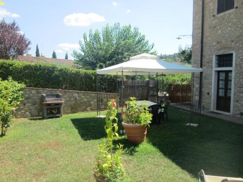 a garden with an umbrella and a table and a grill at Casa ai Carfini in Poggibonsi