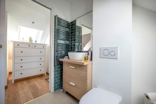 La salle de bains est pourvue d'un lavabo et d'une commode avec un miroir. dans l'établissement Maison équipée proche Paris, à Saint-Ouen