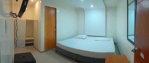 um pequeno quarto com uma cama branca e um closet em AW Connect Airport em Bogotá