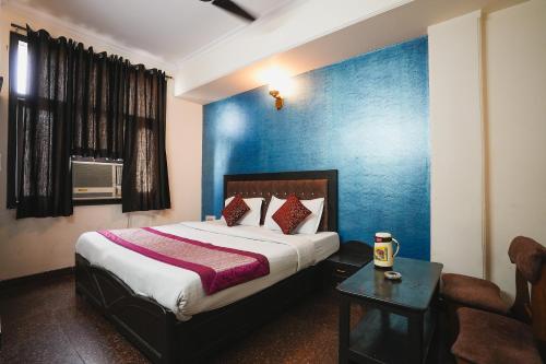 ein Schlafzimmer mit einem Bett und einer blauen Wand in der Unterkunft Hotel Vardhmaan Inn in Neu-Delhi