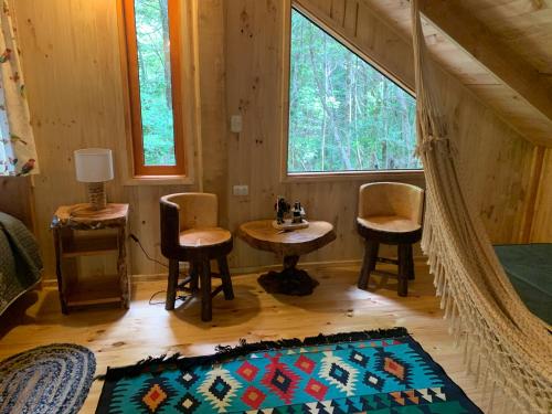 a room with two chairs and a table in a cabin at Casa Encantada HuiloHuilo in Puerto Fuy