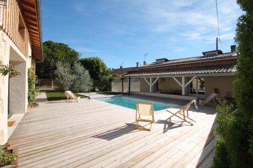 eine Terrasse mit 2 Stühlen und einem Pool in der Unterkunft La Maison Bois Carré in Saint-Yzans-de-Médoc