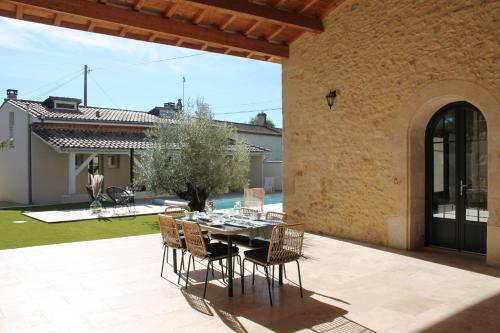 a patio with a table and chairs on a patio at La Maison Bois Carré in Saint-Yzans-de-Médoc