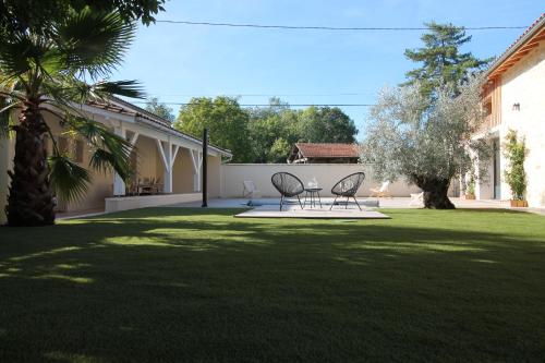 two chairs and a table in a yard at La Maison Bois Carré in Saint-Yzans-de-Médoc