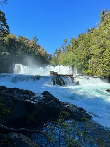 a waterfall in the middle of a river at Casa Encantada HuiloHuilo in Puerto Fuy