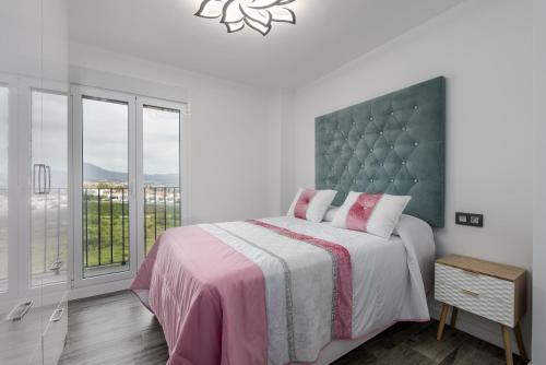 a bedroom with a bed and a large window at Urbanización jardines del mar in Castillo de Sabinillas