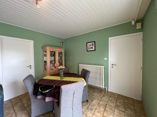 a dining room with a table and chairs and green walls at Villa Gaupin Adults Only in Koksijde