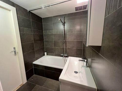 La salle de bains est pourvue d'un lavabo et d'une baignoire. dans l'établissement Villa Gaupin Adults Only, à Coxyde