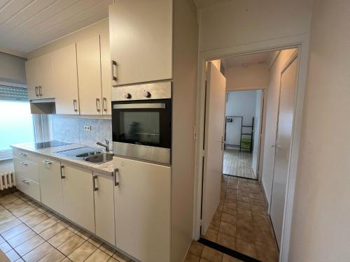 a kitchen with white cabinets and a sink at Villa Gaupin Adults Only in Koksijde