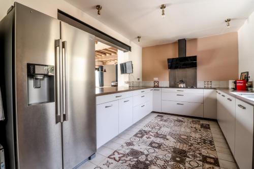une cuisine avec des armoires blanches et un réfrigérateur en acier inoxydable dans l'établissement Au Petit Bonheur, à Maurens