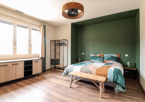 - une chambre avec un mur vert et un lit avec un banc dans l'établissement Au Petit Bonheur, à Maurens