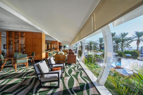 een lobby met uitzicht op de oceaan en palmbomen bij Noga by Isrotel Collection - The Renewed Ganim Hotel in Ein Bokek