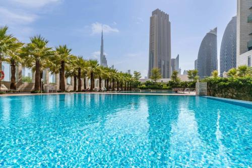 a large swimming pool with palm trees in a city at Silkhaus cozy studio in heart of DIFC Burj Daman in Dubai