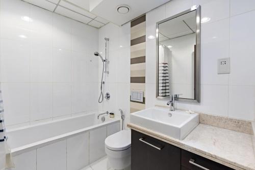 ein Badezimmer mit einem Waschbecken, einem WC und einem Spiegel in der Unterkunft Silkhaus with full Burj Khalifa & fountain view 1BDR in Downtown in Dubai