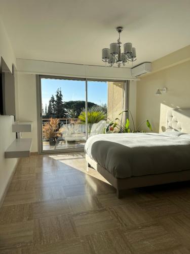 une chambre avec un grand lit et une grande fenêtre dans l'établissement The Place *****, à Cannes