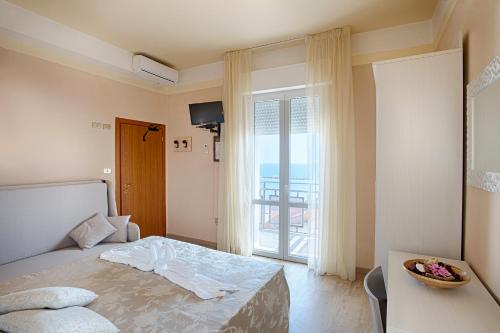 a bedroom with a bed and a large window at Hotel Barca D'Oro in Bellaria-Igea Marina