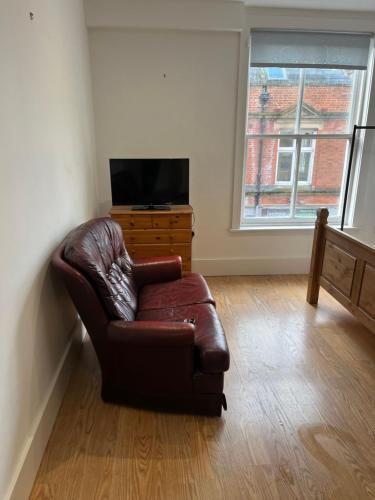 a living room with a leather couch and a television at Aspect apartments in Chesham