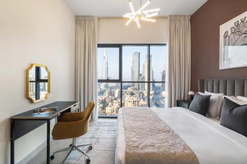 a bedroom with a large bed with a desk and a window at Silkhaus Burj Khalifa view large 2BDR in new tower in Dubai