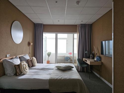a hotel room with a bed and a desk and a television at Hotel Restaurant Solskin in Vlissingen