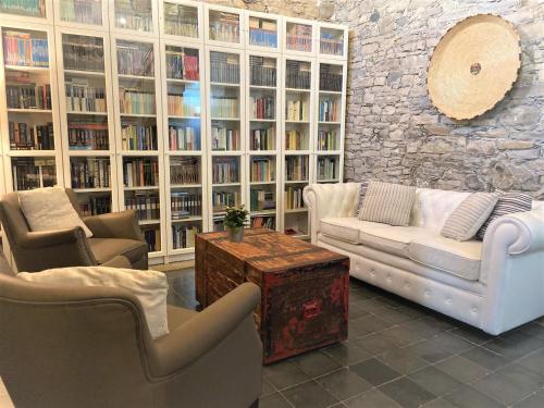 a living room with couches and chairs in a library at Bissantica, heritage and charm in rural Sardinia in Lunamatrona