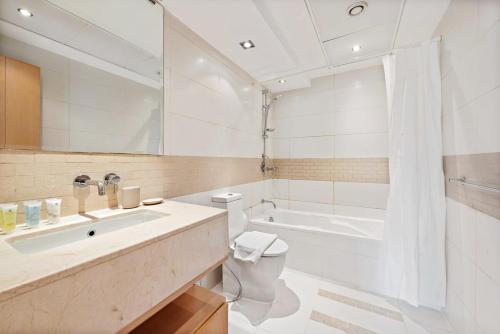 een badkamer met een wastafel, een toilet en een bad bij Silkhaus Modern 1BDR in Marina Close to Beach in Dubai